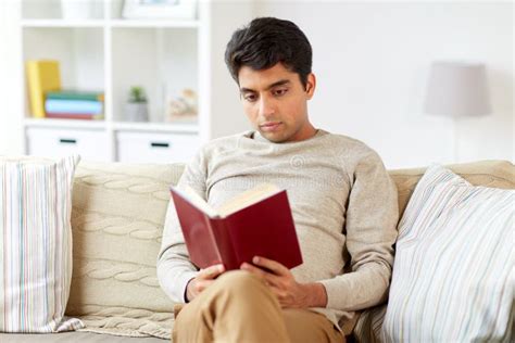 Man Sitting on Sofa and Reading Book at Home Stock Photo - Image of ...