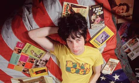 a young man laying in bed next to an american flag with books and ...