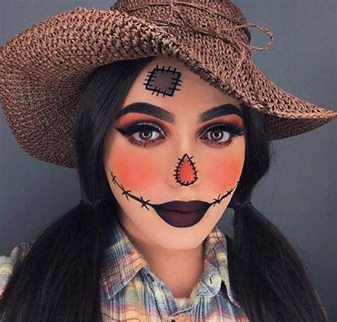a woman with makeup painted to look like a scarecrow wearing a straw ...