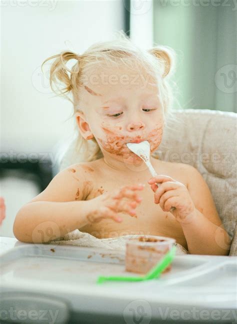 Baby with dirty face enjoying her meal 27817762 Stock Photo at Vecteezy