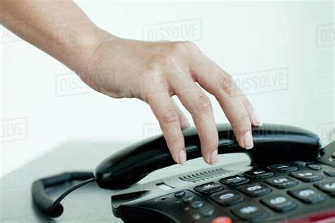 Hand picking up telephone receiver, cropped - Stock Photo - Dissolve