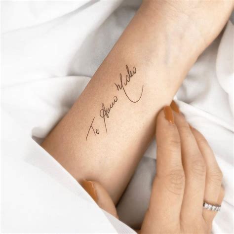 "Te amo mucho" lettering tattoo on the inner forearm.