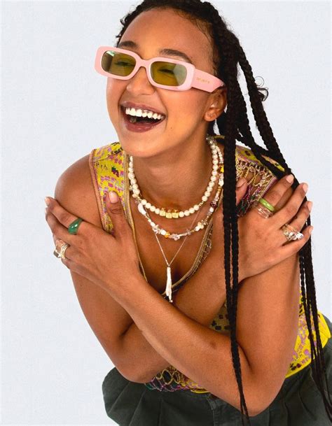 a woman wearing sunglasses and smiling with her hands on her chest ...