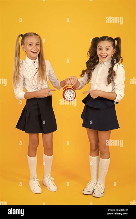 This clock is perfect. Happy little girls pointing at vintage alarm clock on yellow background ...