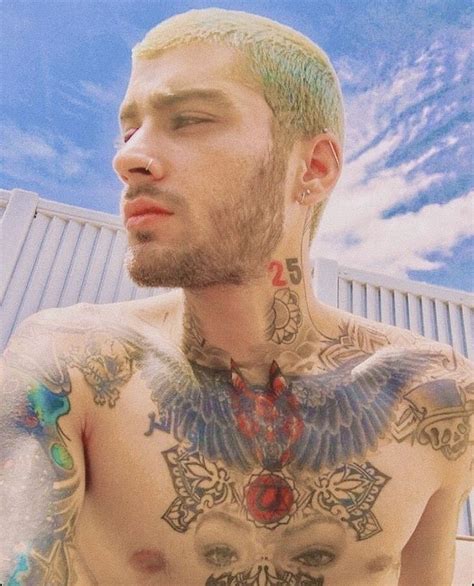 a man with green hair and tattoos on his chest looking at the camera ...