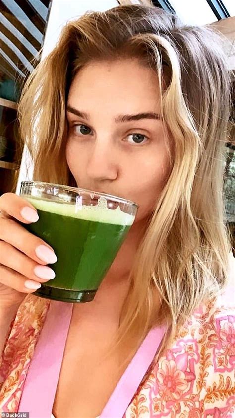 a woman drinking a green smoothie from a glass