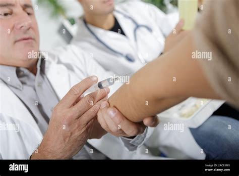 doctor making an injection on patients arm Stock Photo - Alamy