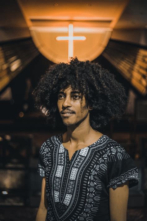 Young black man with curly hair against neon cross · Free Stock Photo