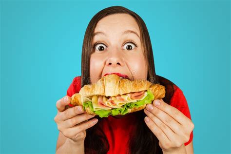Young Woman Eats Croissant with Ham and Cheese on Blue Background Stock ...