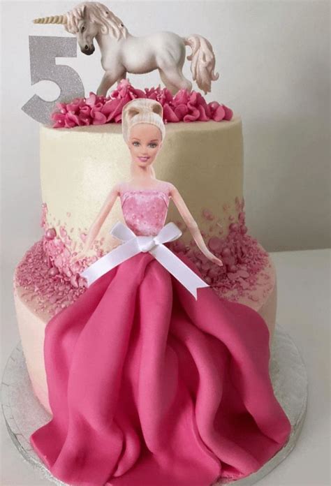 a pink and white cake with a barbie doll on top that has the number ...