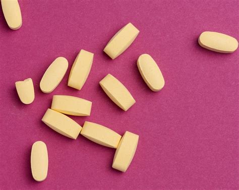 Premium Photo | Yellow oval tablets on a pink background top view