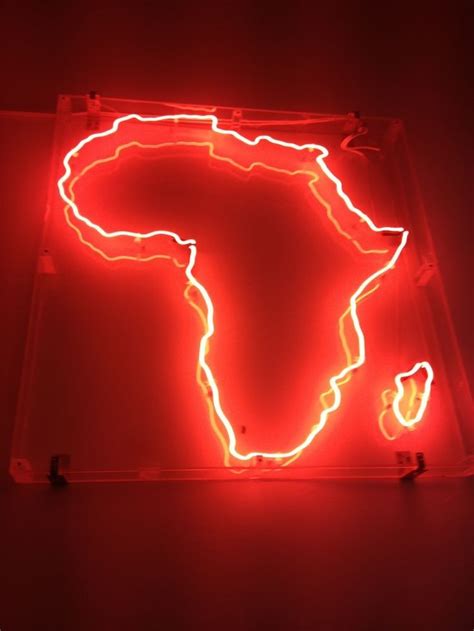 a neon sign that is lit up in the shape of a africa map on a red wall