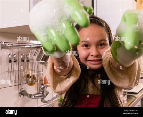 Tween Asian American girl washing dishes, showing foamy gloves with funny expression Stock Photo ...