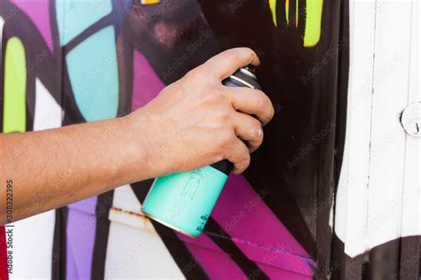 Graffiti artist painting with aerosol spray on the wall at Favela in ...