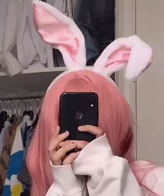 a person with pink hair and bunny ears taking a selfie