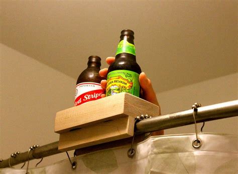 two bottles of beer sitting on top of a wooden shelf next to a shower curtain