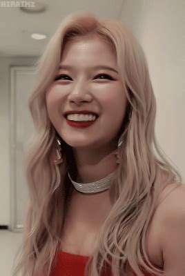 a woman with long blonde hair wearing a red dress and silver choker smiling at the camera