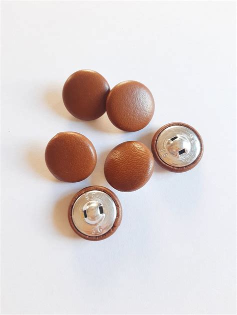 four brown buttons on a white surface