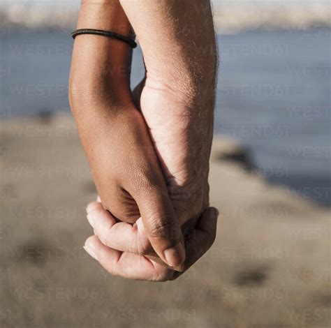 Close-up of couple holding hands at the waterfront stock photo