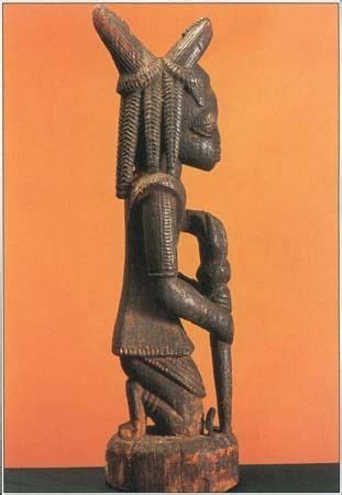 This carved wood sculpture shows Eshu, the trickster god of the Yoruba people of Nigeria in West ...