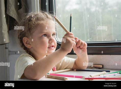 Four-year girl draws pencil in a notebook for a side table in the second-class train carriage ...