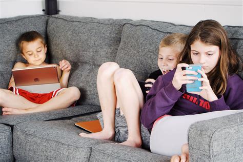 Children lying on sofa and using gadgets · Free Stock Photo