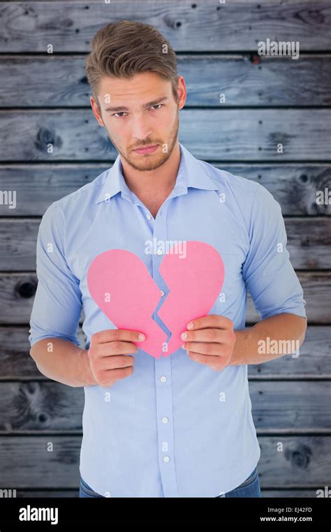 Composite image of sad man holding a broken heart Stock Photo - Alamy