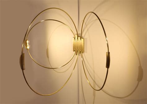 Rings Sconce, is brass LED lighting. Each hoop moves back and forth to change the light and ...