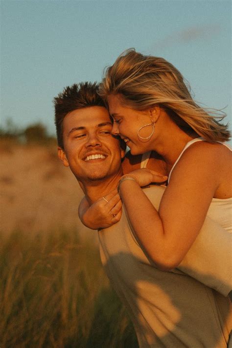 Girl and guy running around in the sand dunes of Lake Michigan in the Summer at a photoshoot ...