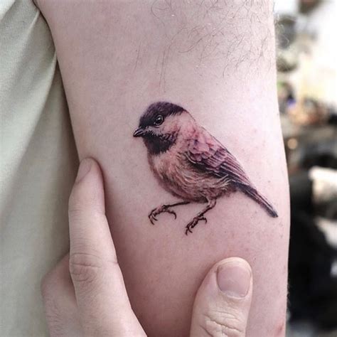 a small bird tattoo on the left arm