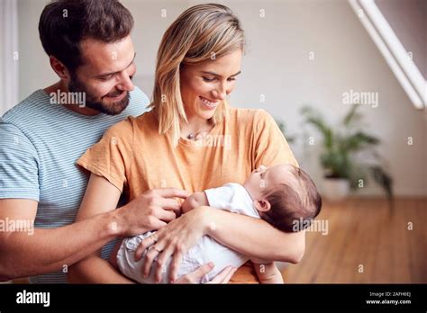 Loving Parents Holding Newborn Baby At Home In Loft Apartment Stock ...