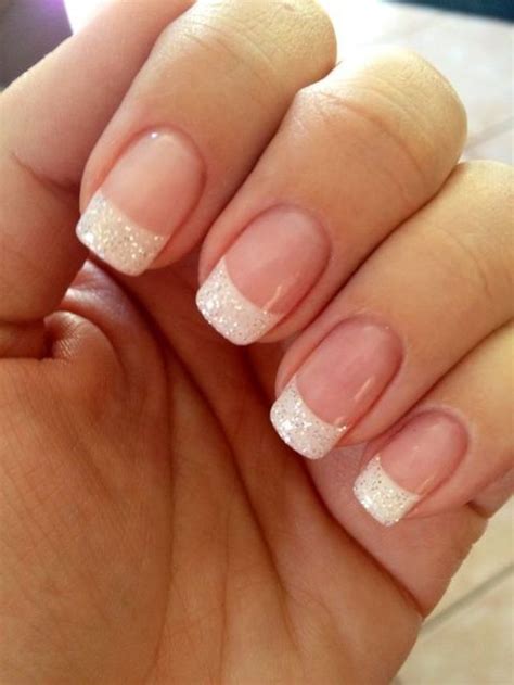a woman's hand with french manies and glitters on it, holding her nails