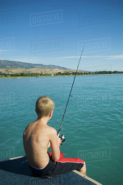 Boy fishing off dock in lake, Utah, United States - Stock Photo - Dissolve