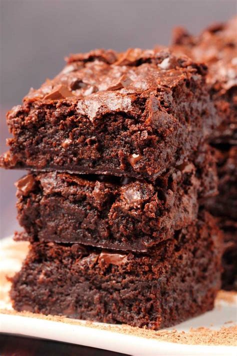 three chocolate brownies stacked on top of each other with one bite ...