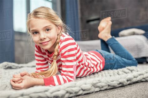 Pretty little girl lying on floor and smiling at camera - Stock Photo - Dissolve