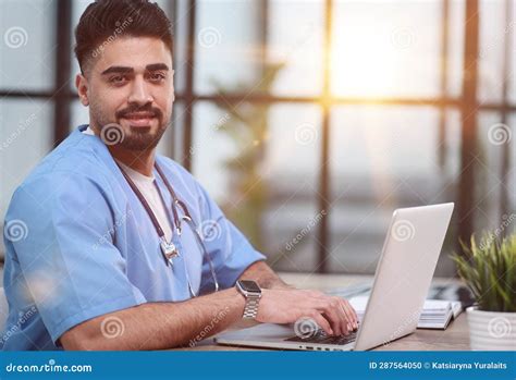 Young Male Doctor Works on Laptop Computer at Table in Medical Office ...