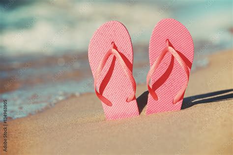 Foto Stock Pink flip flops in the sand on the beach | Adobe Stock