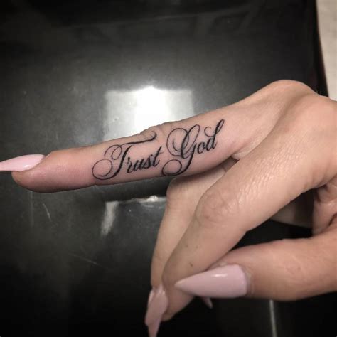 "Trust god" script finger tattoo.