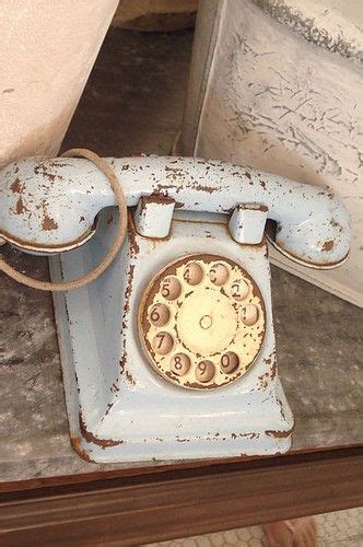 an old fashioned phone is sitting on the floor next to a wall with peeling paint