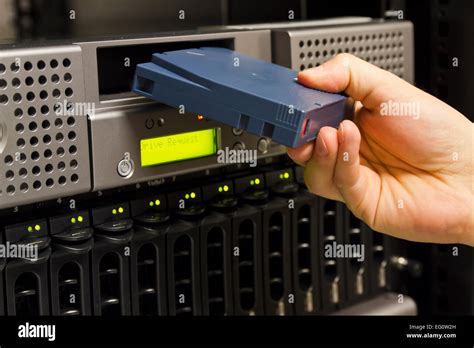 A close-up of a IT engineer / technician insert a backup tape in a ...