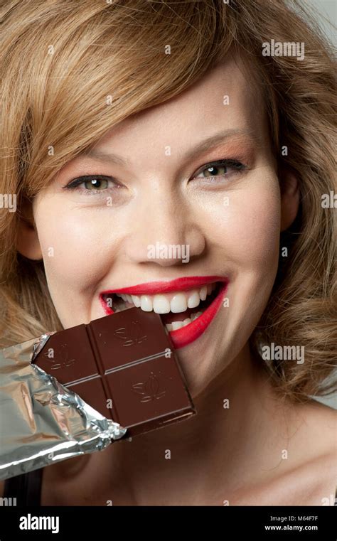 Happy woman biting into bar of dark chocolate Stock Photo - Alamy
