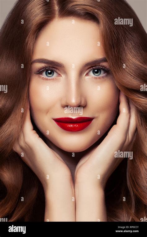 Perfect female face closeup portrait. Pretty woman with curly shiny hair and red lips makeup ...