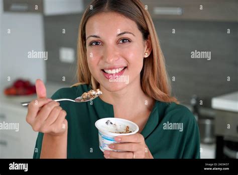 Beautiful young woman eating greek yogurt with muesli at home Stock Photo - Alamy