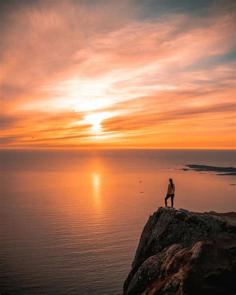 A Person Standing on a Cliff Overlooking the Sea during Golden Hour ...