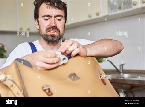 Do-it-yourselfer looks skeptical at a spare part for a kitchen sink repair Stock Photo - Alamy