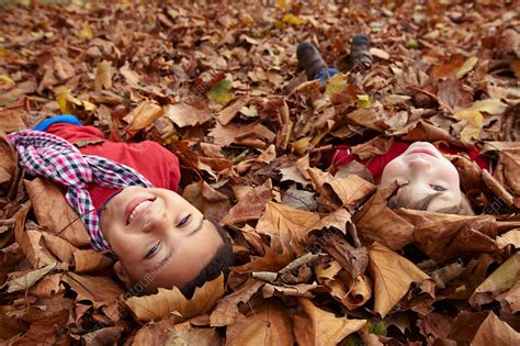 Children playing in autumn leaves - Stock Image - F005/2770 - Science Photo Library