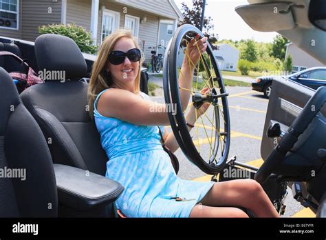 Woman with spinal cord injury pulling wheel from wheelchair into her adaptive vehicle Stock ...