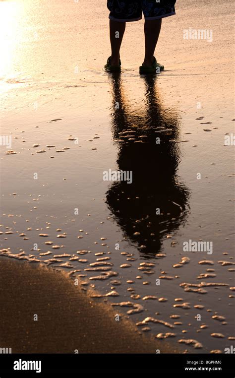 Man on a beach at sunset Stock Photo - Alamy