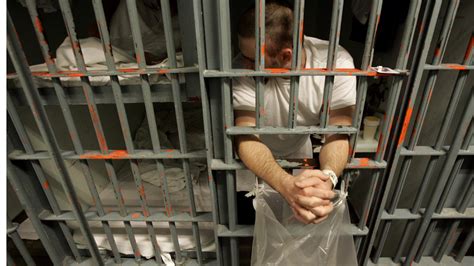 An inmate leans out the bars of his cell in a one -prisoner-per-cell ...