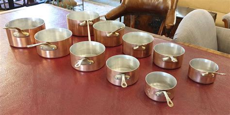 BATTERIE DE CUISINE, ten pans, copper with brass handles. (10)